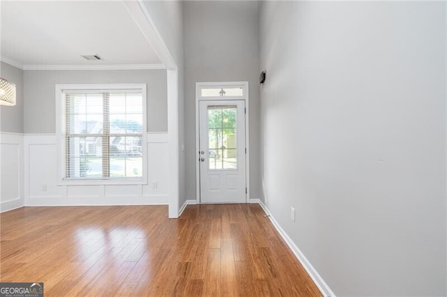 doorway to outside with crown molding and light hardwood / wood-style floors