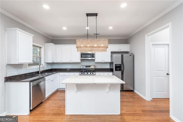 kitchen featuring appliances with stainless steel finishes, white cabinetry, hanging light fixtures, sink, and a kitchen island