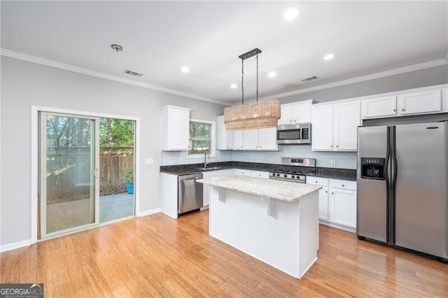 kitchen with pendant lighting, white cabinets, appliances with stainless steel finishes, a center island, and sink