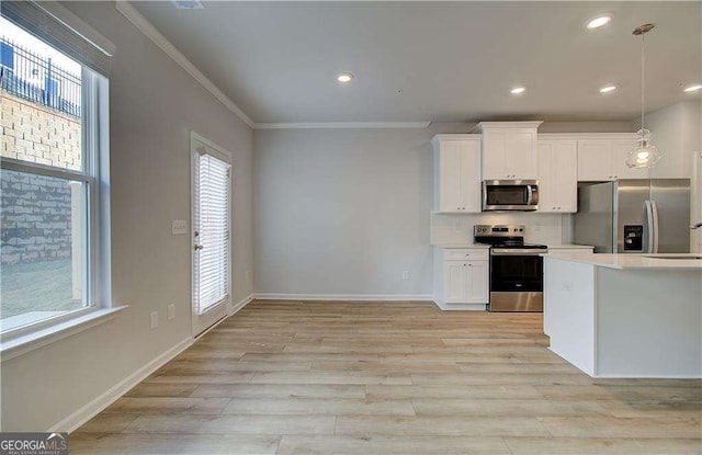 kitchen featuring crown molding, pendant lighting, appliances with stainless steel finishes, white cabinetry, and a wealth of natural light