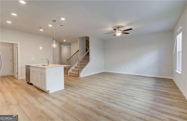 kitchen featuring pendant lighting, an island with sink, sink, ceiling fan, and light hardwood / wood-style flooring