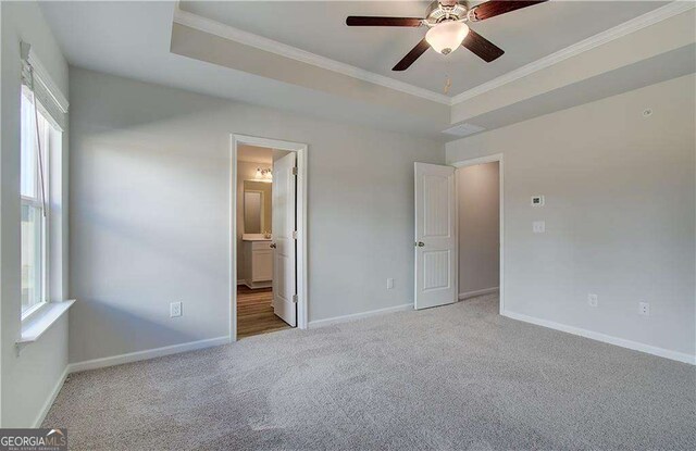 unfurnished room with light carpet, ornamental molding, ceiling fan, and a raised ceiling