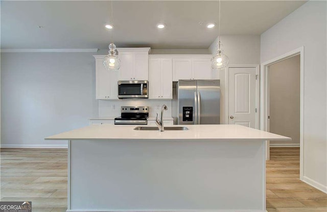 kitchen with appliances with stainless steel finishes, sink, decorative light fixtures, white cabinetry, and an island with sink