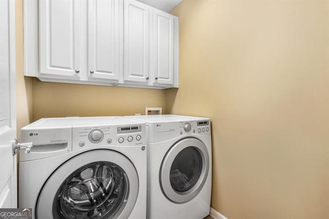 clothes washing area with baseboards, cabinet space, and washing machine and clothes dryer