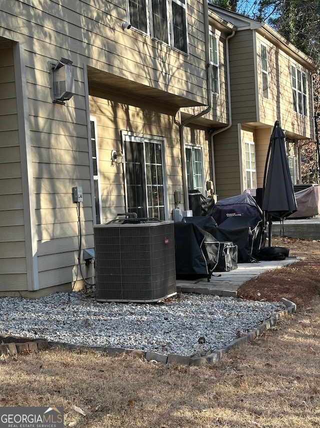 rear view of property with central AC unit and an AC wall unit