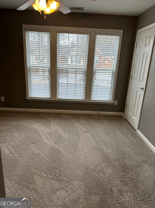 empty room with carpet floors, visible vents, baseboards, and a ceiling fan