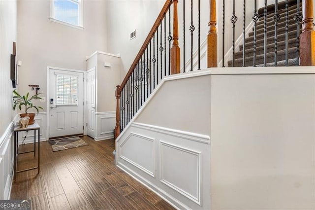 foyer entrance with wainscoting, a decorative wall, a wealth of natural light, and wood finished floors