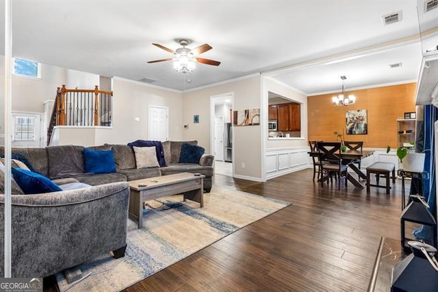 living room featuring ceiling fan with notable chandelier, ornamental molding, and dark hardwood / wood-style flooring