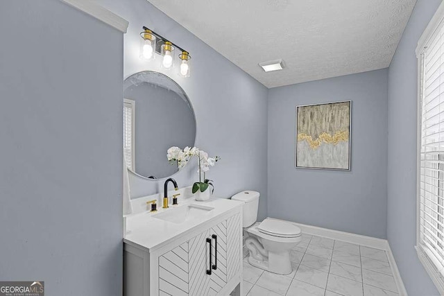 half bathroom with marble finish floor, toilet, a textured ceiling, vanity, and baseboards