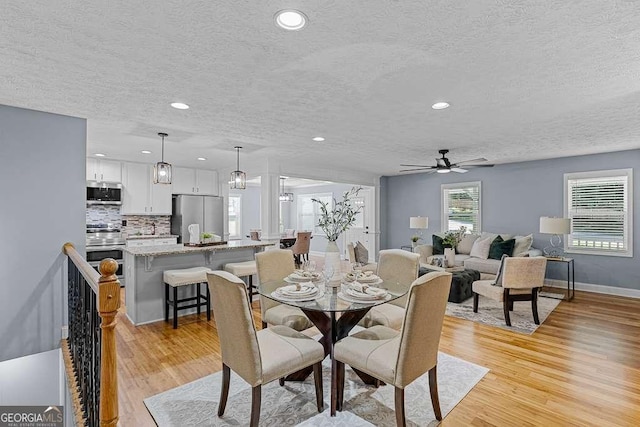 dining room with a textured ceiling, recessed lighting, a ceiling fan, baseboards, and light wood finished floors