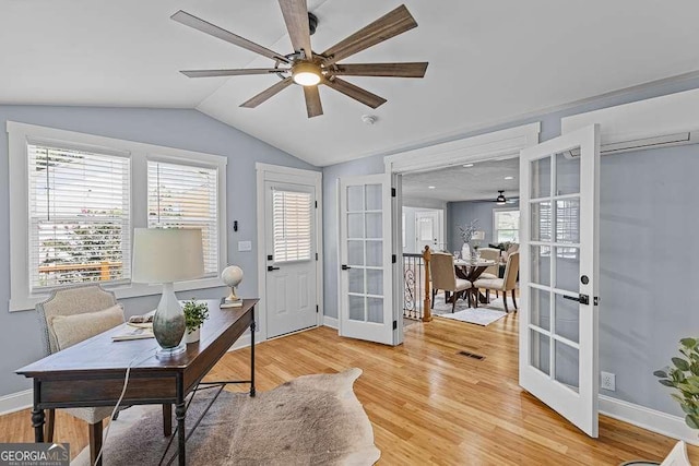 home office featuring french doors, visible vents, light wood-style flooring, a ceiling fan, and vaulted ceiling