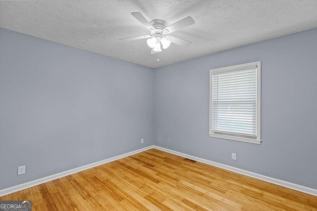 unfurnished room featuring light wood-style flooring, a ceiling fan, visible vents, and baseboards