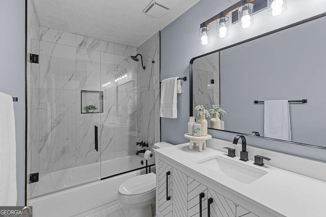 bathroom with shower / bath combination with glass door, visible vents, toilet, vanity, and a textured ceiling