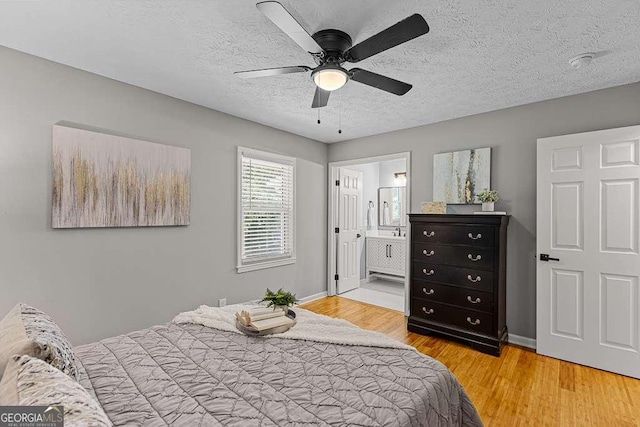 bedroom featuring a textured ceiling, ceiling fan, connected bathroom, baseboards, and light wood finished floors