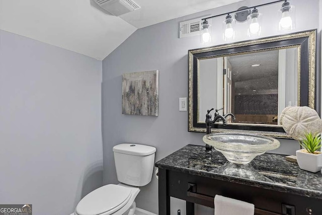 bathroom featuring toilet, visible vents, vaulted ceiling, and vanity