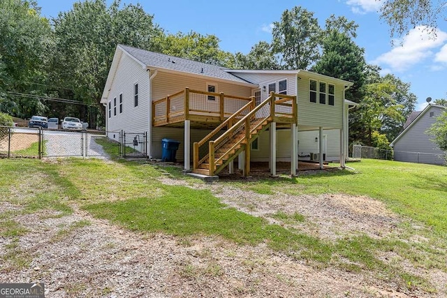 back of property featuring a lawn, a gate, fence, a wooden deck, and stairs