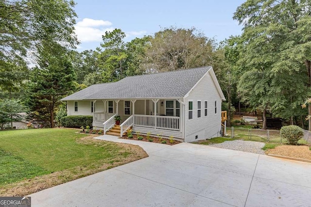 ranch-style house featuring roof with shingles, fence, a porch, and a front yard