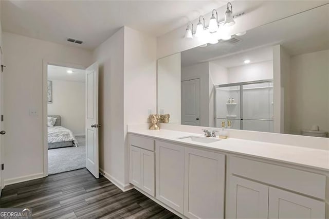 bathroom with hardwood / wood-style flooring, toilet, walk in shower, and vanity