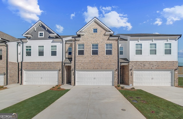 multi unit property featuring a garage, brick siding, and driveway