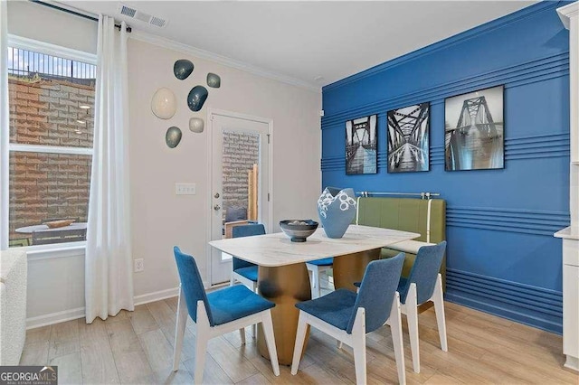 dining space featuring ornamental molding, wood finished floors, visible vents, and baseboards