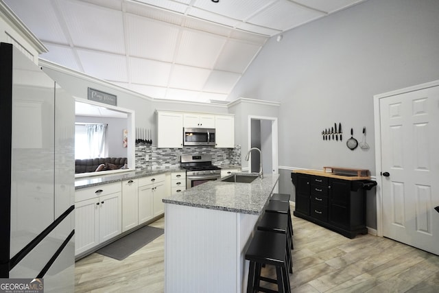 kitchen featuring sink, a breakfast bar area, appliances with stainless steel finishes, white cabinetry, and an island with sink