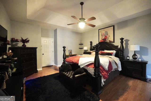 bedroom featuring a tray ceiling, wood-type flooring, and ceiling fan