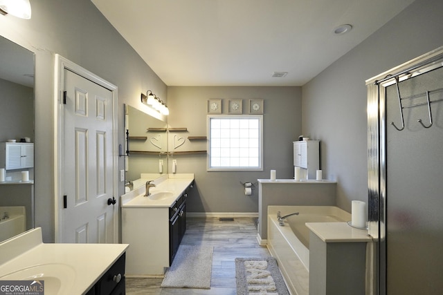 bathroom featuring vanity, wood-type flooring, and a tub to relax in