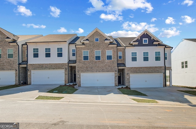 view of property with a garage, concrete driveway, and brick siding