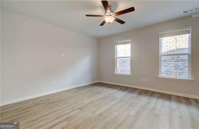 empty room with light wood-type flooring, visible vents, baseboards, and a ceiling fan