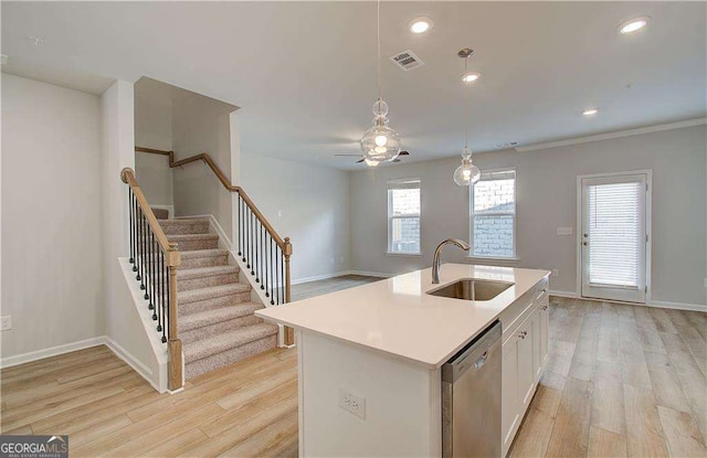 kitchen with stainless steel dishwasher, light wood-style flooring, pendant lighting, and a sink