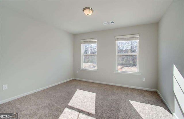 carpeted spare room with visible vents and baseboards