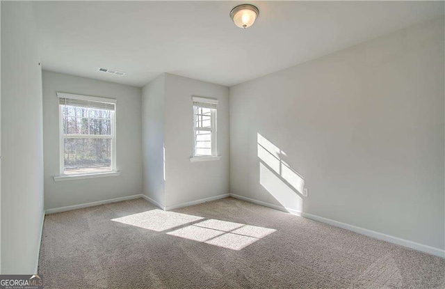 spare room featuring baseboards, visible vents, and light colored carpet