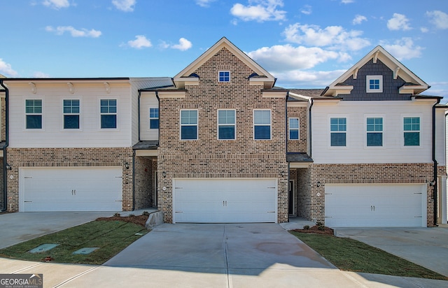 multi unit property featuring a garage, concrete driveway, and brick siding