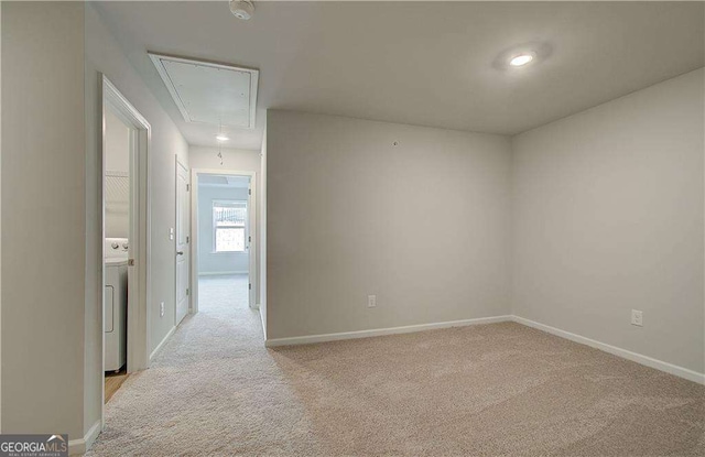 empty room with carpet floors, washer / dryer, attic access, and baseboards