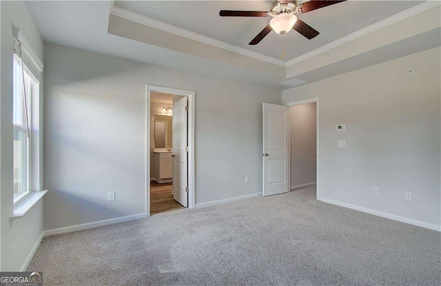 unfurnished bedroom with carpet, a tray ceiling, and baseboards