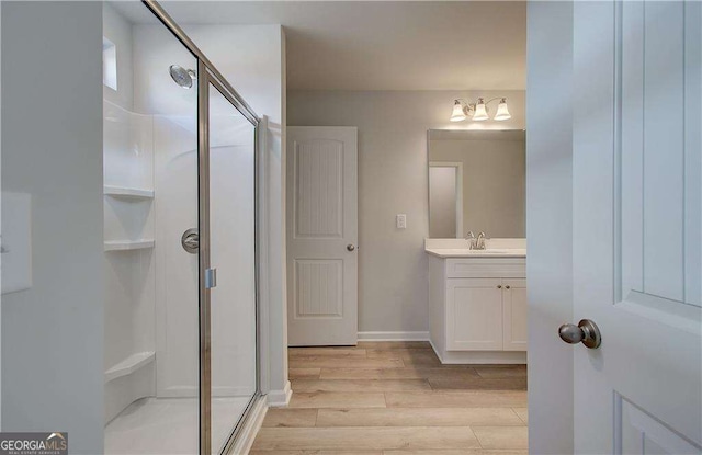 full bathroom with baseboards, a shower stall, vanity, and wood finished floors