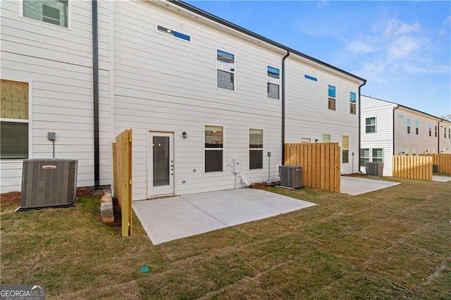 rear view of property featuring fence, a lawn, central AC, and a patio