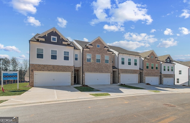 multi unit property featuring an attached garage, a residential view, concrete driveway, and brick siding