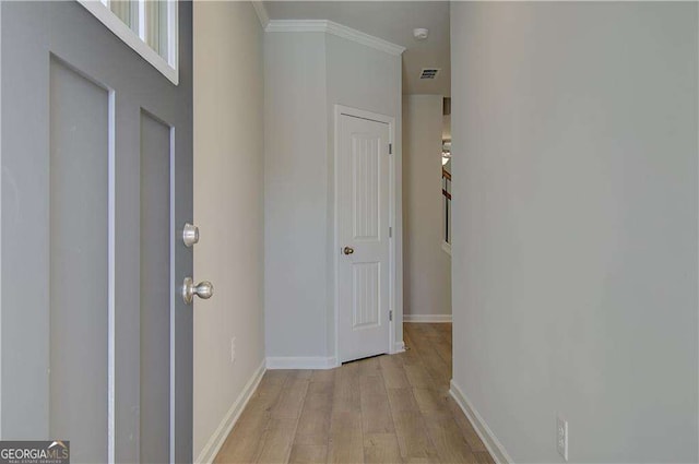 interior space with light wood-style floors, visible vents, baseboards, and crown molding