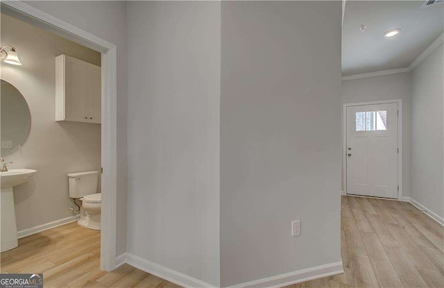 foyer featuring light wood finished floors, visible vents, baseboards, and ornamental molding