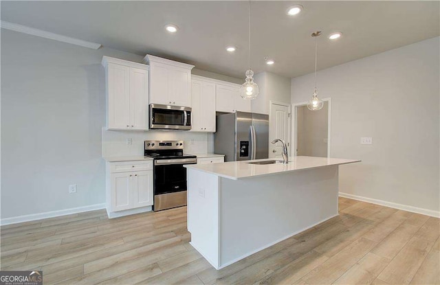 kitchen featuring stainless steel appliances, a sink, light wood-style flooring, and an island with sink