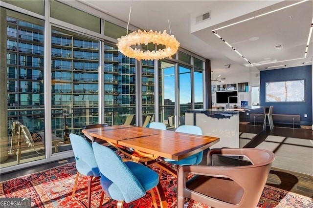 dining room with wood-type flooring, a chandelier, and a wall of windows