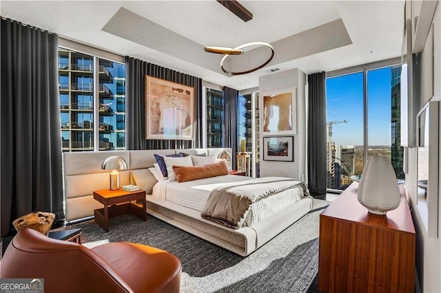 bedroom with a wall of windows and a raised ceiling