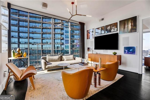 living area with visible vents, a wall of windows, baseboards, and wood finished floors