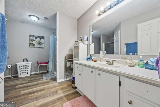 bathroom with wood-type flooring, a textured ceiling, vanity, and a shower with shower curtain