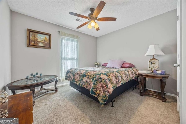 bedroom with ceiling fan, carpet, and a textured ceiling