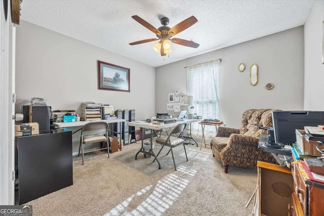 office area with ceiling fan, a textured ceiling, and light carpet