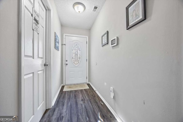 doorway with dark wood-type flooring and a textured ceiling