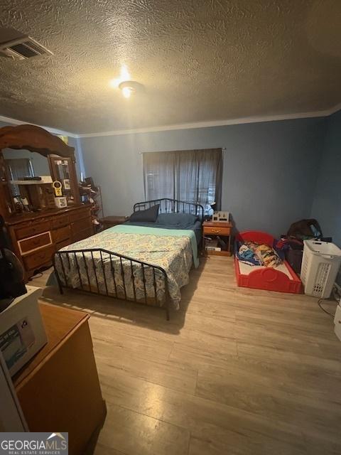 bedroom featuring crown molding, hardwood / wood-style flooring, and a textured ceiling