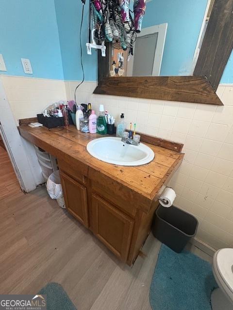 bathroom featuring hardwood / wood-style floors, toilet, tile walls, and vanity